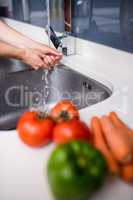 Woman washing hands in sink at kitchen counter