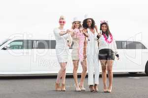 Frivolous women drinking champagne next to a limousine