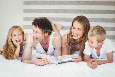 Happy family reading book on bed