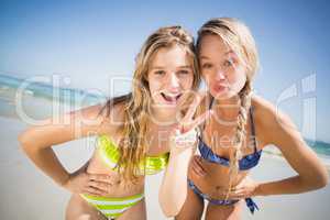 Two happy women pouting and gesturing on the beach
