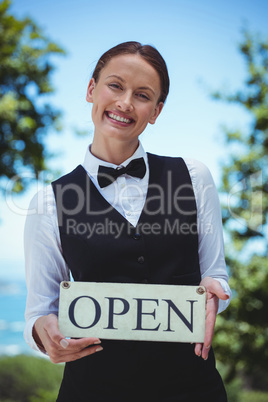 Smiling waitress holding open sign