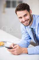 Young businessman using mobile phone at home