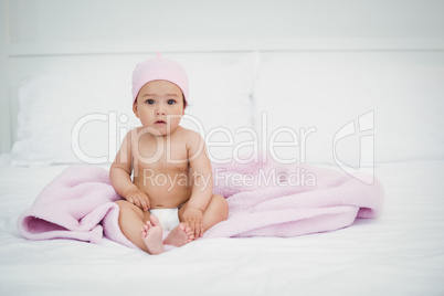 Portrait of cute baby sitting on bed