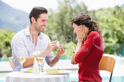 Man giving engagement ring to astonished woman