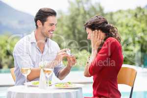 Man giving engagement ring to astonished woman
