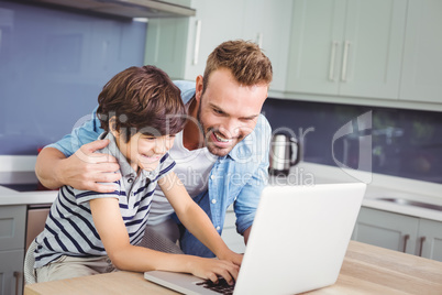 Smiling father and son working on laptop
