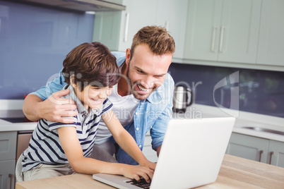 Smiling father and son working on laptop Smiling father and son working on laptop