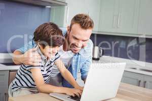 Smiling father and son working on laptop