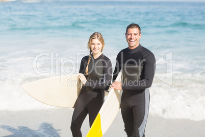 Portrait of couple with surfboard walking on the beach