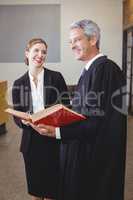 Male lawyer with book standing by female colleague