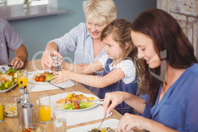 Grandmother assisting granddaughter while having breakfast