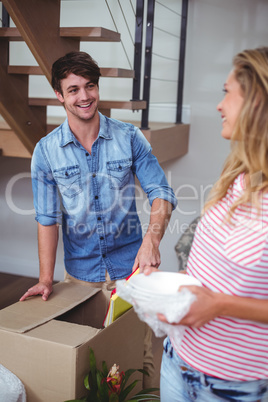 Smiling woman looking at man unpacking books