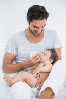 Father feeding milk to daughter at home