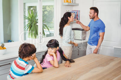 Children sitting at table with parents quarreling