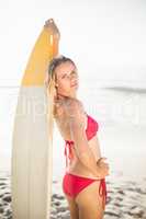 Woman in bikini standing with a surfboard on the beach