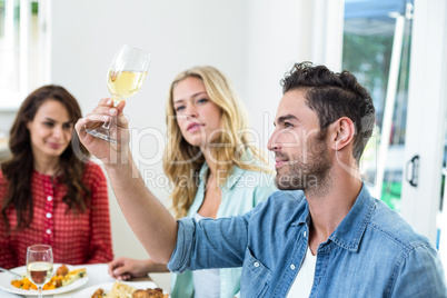 Smiling man holding white wine glass with friends