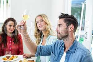 Smiling man holding white wine glass with friends