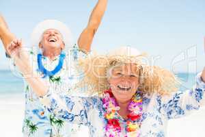 Senior couple with arms up on the beach