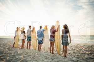 Friends holding surfboard on the beach