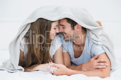 Happy couple romancing under blanket