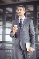 Businessman holding disposable cup and digital tablet