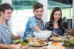 Friends having meal at table in house