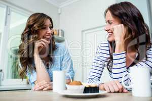 Laughing friends holding coffee mugs at table
