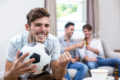 Young man watching soccer match while friends in background