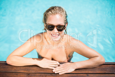 Beautiful woman wearing sunglasses leaning by poolside