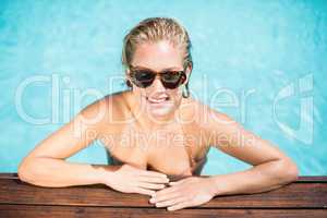 Beautiful woman wearing sunglasses leaning by poolside