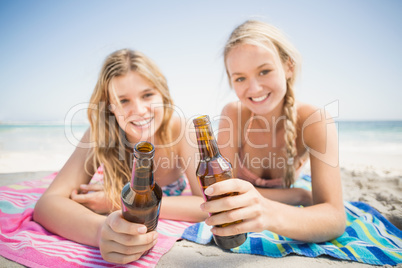 Happy women lying on the beach with beer bottle