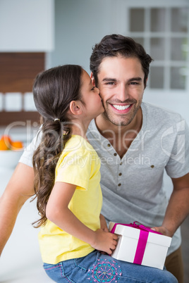 Daughter kissing father holding gift box