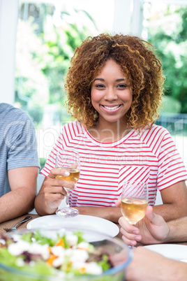 Happy young woman drinking wine with friends