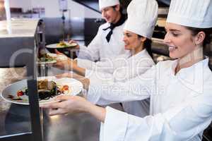 Chefs handing dinner plates through order station
