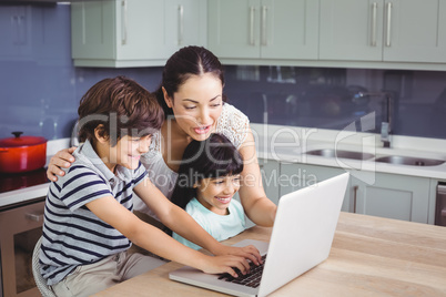 Smiling mother and children working on laptop