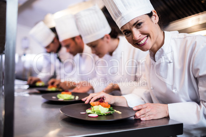 Smiling chef with garnished food plate in the kitchen