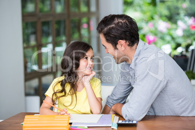 Smiling father and daughter sitting at desk