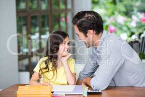 Smiling father and daughter sitting at desk