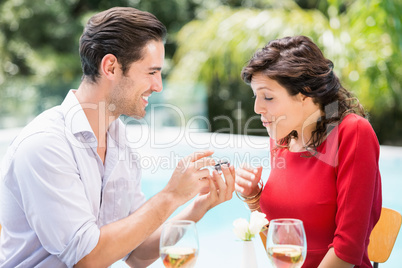 Young man giving engagement ring to surprised woman