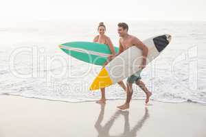 Couple with surfboard running on the beach
