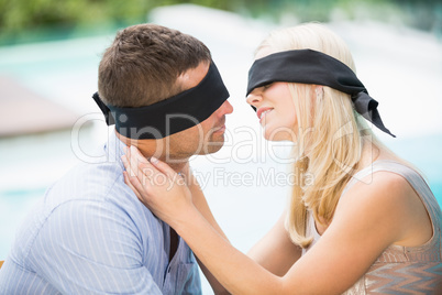 Blindfolded couple kissing