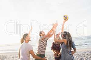 Happy friends playing beach volleyball