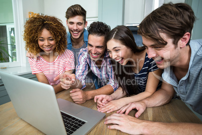 Young friends laughing while looking in laptop on table