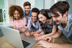 Young friends laughing while looking in laptop on table