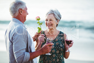 Senior couple holding rose and red wine glasses