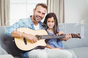 Portrait of happy father playing guitar with daughter