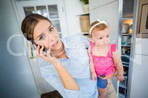 Tensed woman talking on mobile phone while carrying baby girl