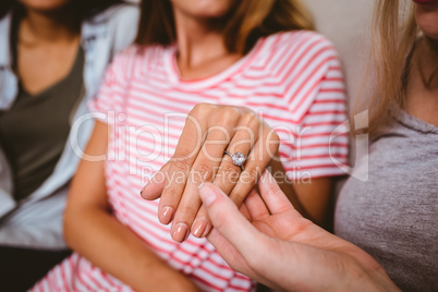 Midsection of  woman showing engagement ring to friends