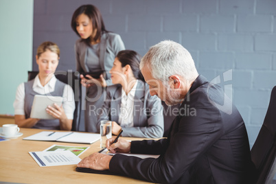 Businessman writing a report in conference room