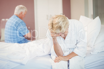 Tensed senior couple sitting in bedroom